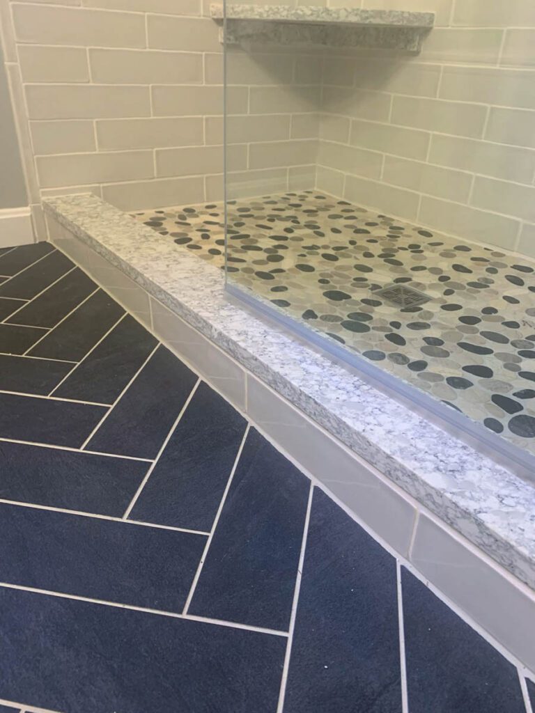 Fishbone tile next to pebbled stone shower floor